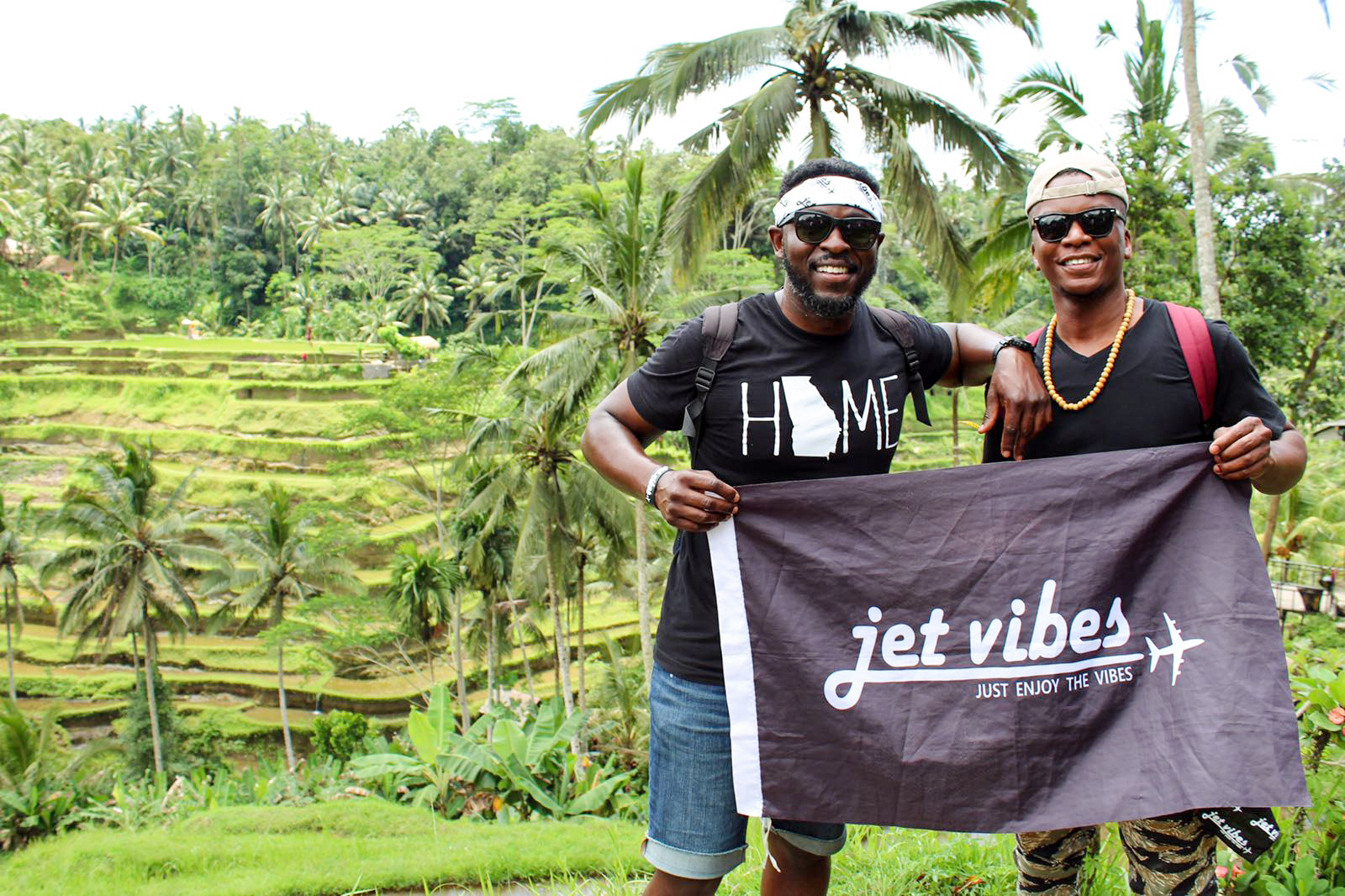 Jet Vibes founders Jeremiah Ransaw and Jet Wright holding the brand flag in Bali