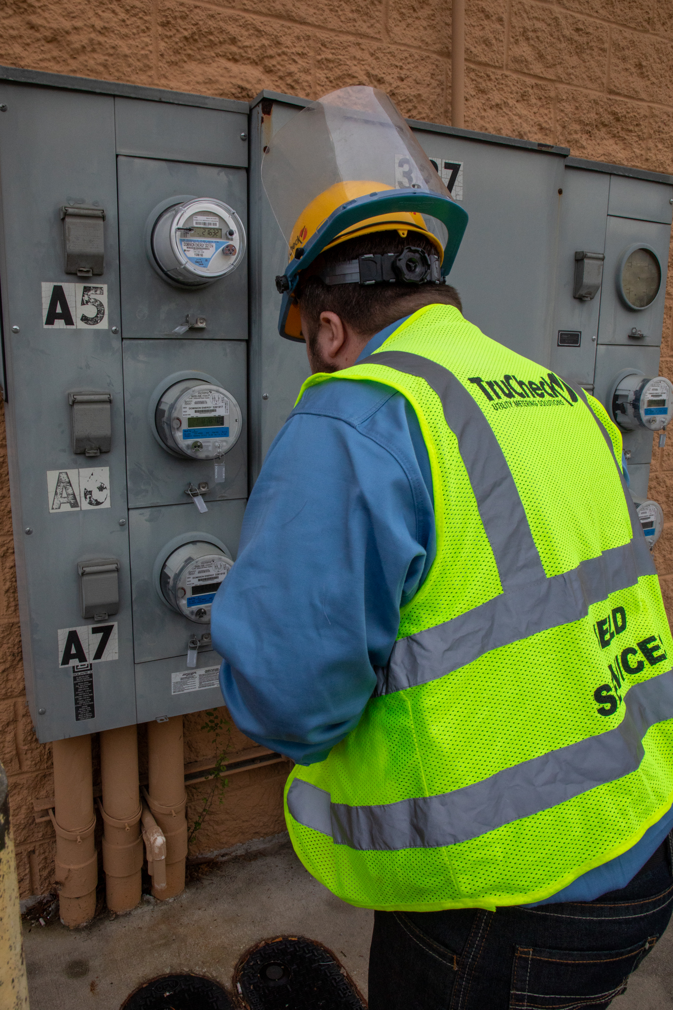 TruCheck field technician wearing branded safety gear while inspecting utility meter equipment.